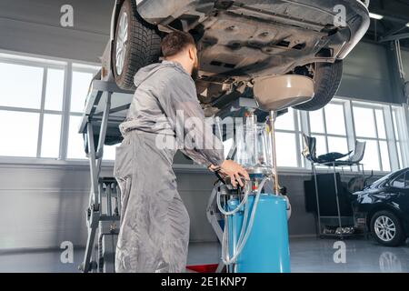 Car Mechanic Replacing Oil in Motor Engine. Auto service shop Stock Photo