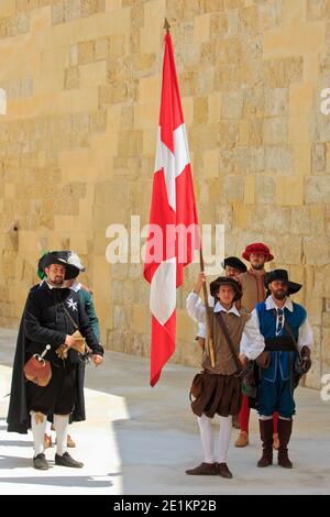 An officer of the Order of St. John with a standard bearer and soldiers at Fort Saint Elmo in Valletta, Malta Stock Photo