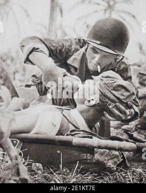 First aid to a wounded man on the battlefield. The infantry of the American Navy has just reconquered the island of Guam (The Second Battle of Guam. Stock Photo