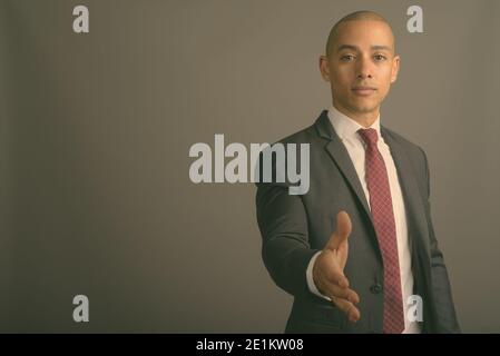 Handsome bald businessman wearing suit against gray background Stock Photo