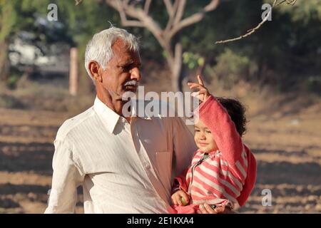 A beautiful Indian little child is cropped by hand and the Indian grandfather is seen cropping in the garden, india Stock Photo