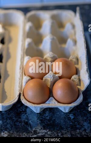 Cardboard carton retail packaging with four fresh brown hens eggs in a high angle close up view Stock Photo