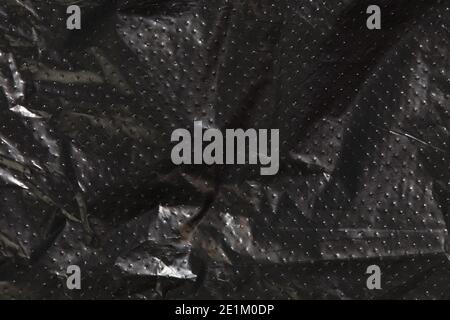 black cellophane bag background texture. plastic surface is wrinkly and tattered making abstract pattern. Stock Photo