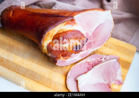 juicy smoked pork shank, delicious meat appetizer, sliced pieces on a wooden board, food Stock Photo