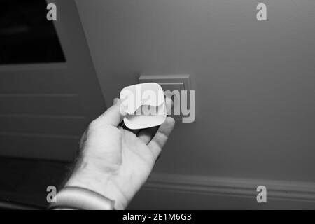 Male hand holding night light next to power outlet - ready to be plugged Stock Photo