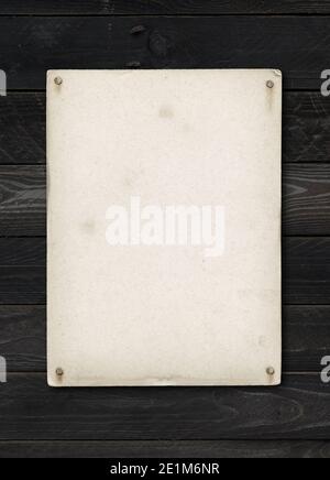 Old textured paper sheet nailed on a black wood table. vertical Mockup Stock Photo