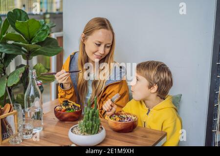 Mother and son eating Raw Organic Poke Bowl with Rice and Veggies close-up on the table. Top view from above horizontal Stock Photo