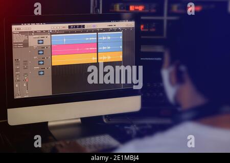 Cropped image of One man wearing face mask produce electronic music in project home studio. Stock Photo