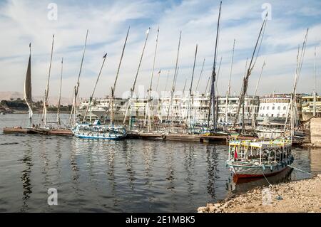 Luxor. Colourful scenes on the Corniche with local fishing boats and river cruise liners moored at the Egyptian town of Luxor previously known during the time of ancient Egypt as Thebes located on the River Nile Stock Photo