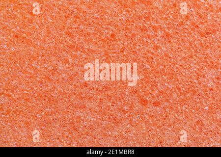 Orange foam kitchen sponge texture. Full frame macro photography of porous synthetic material. Abstract pattern background for cleaning and housework. Stock Photo