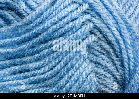 Cropped skein of pale blue woolen knitting thread texture. Ball of soft woolen yarn full frame macro photography. Knitting threads for handicraft. Stock Photo