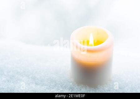 Candle burning on the snow snow or snowy surface, winter background with snowflakes, close up Stock Photo