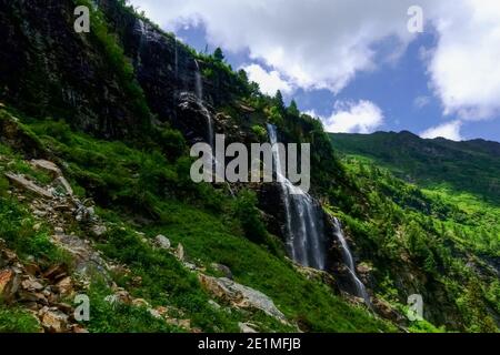 high waterfall over rocks while hiking in the mountains on vacation Stock Photo