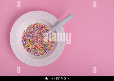 colorful soup in white plate with spoon on pink background Stock Photo