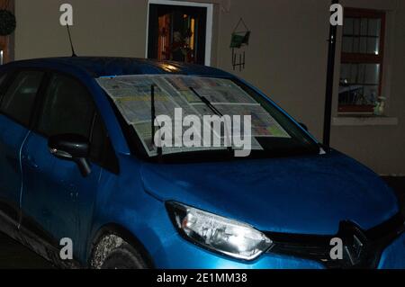 With temperatures set to go below zero again, Met Eireann have issued a weather warning for snow and ice for the entire country. A car owner places newspapers on their windscreen to prevent ice from covering the glass. Credit; ED/Alamy Live News Stock Photo