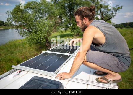 Man on top of a camper van next to solar panels Stock Photo