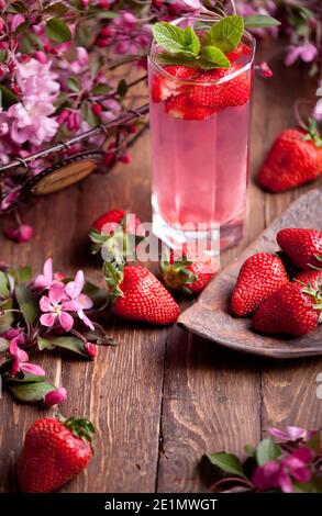 strawberry lemonade with strawberries, mint and flowers on wooden table surface background and copyspace Stock Photo