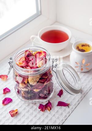 Using dry rose petals to make rose potpourri wich is great for home smell. Great way to preserving flowers and memories. Mason jar lid open. Stock Photo
