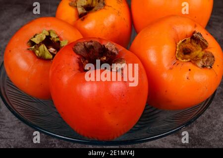 Group of Ripe orange persimmon fruit.Persimmon fruits in plate, rustic background, Hurma fruit Stock Photo