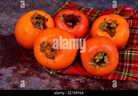 Group of Ripe orange persimmon fruit.Persimmon fruits in plate, rustic background, Hurma fruit Stock Photo