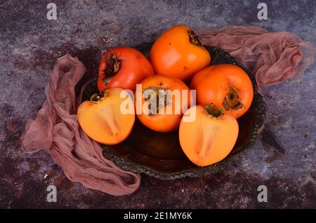Group of Ripe orange persimmon fruit.Persimmon fruits in plate, rustic background, Hurma fruit Stock Photo
