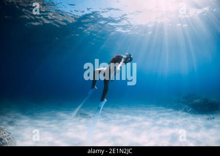 Attractive woman freediver with white fins posing underwater in tropical sea. Stock Photo