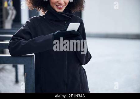 Adult staying outside and watching her phone screen Stock Photo