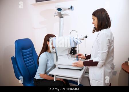 Ophthalmologist doing an eye check on an autorefractor Stock Photo