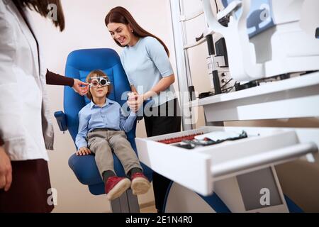 Supportive mother holding boy hand during the eyesight check Stock Photo