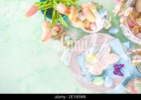 Festive Easter table setting with traditional spring flowers, Easter colorful eggs and sugar cookies. Easter greeting card background copy space Stock Photo