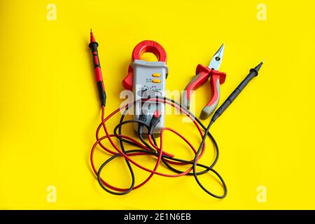 Electrician tools on a yellow background. Multimeter and passages close-up, selective focus. Stock Photo