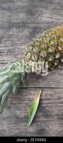A whole pineapple laid down on a wooden table Stock Photo