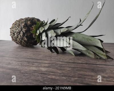 A whole pineapple laid down on a wooden table Stock Photo