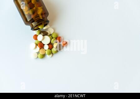 Medicine and pills. Multi-colored medicines on a white background close-up. Brown glass bottle with pills inside on a white background. Multi-colored Stock Photo