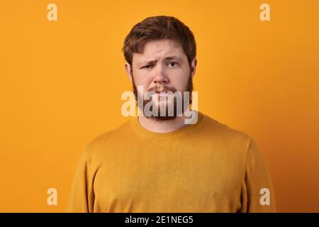 Bewildered man with thick ginger beard, raises eyebrows, reacts on fake news from friend, looks directly at camera, dressed in casual t shirt, isolate Stock Photo