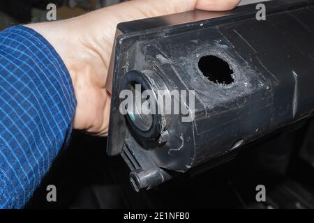 an untidy hole in the body of the laser printer cartridge, which the master refueller of the service center holds in his hand Stock Photo