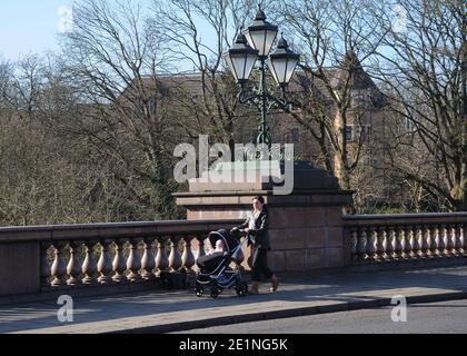 A woman pushing a child in a pushchair over the Kirklee Bridge, built of sandstone and pink granite is one of the finest in Glasgow, Scotland, UK Stock Photo