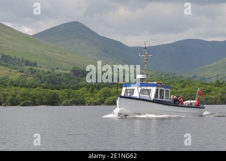 A small pleasure craft takes tourists on a cruise on Loch Lomond with Beinn Eich and Luss hills in the background, Scotland, UK, Europe Stock Photo