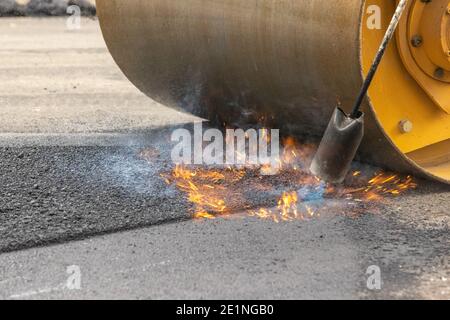 Flame and Steam Rising as asphalt Seam is Sealed and Rolled Smooth Stock Photo
