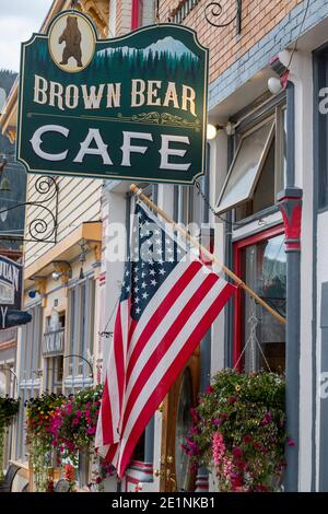 Suspended US flag and street sign for the Brown Bear Cafe, Greene Street, Silverton, Colorado, USA Stock Photo