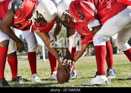 Photo of Football Players in Huddle Holding Football Stock Photo