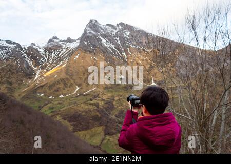 A girl takes pictures of the snowy mountains. Stock Photo
