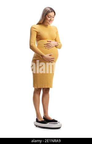 Happy pregnant woman standing on a weight scale isolated on white background Stock Photo
