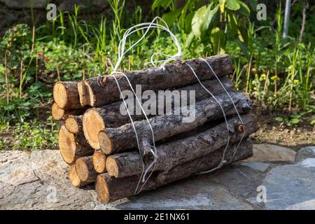 View from above on a bunch of cut pine wood for the fireplace tied with a  white rope lying on stone in the garden. Natural texture Stock Photo - Alamy