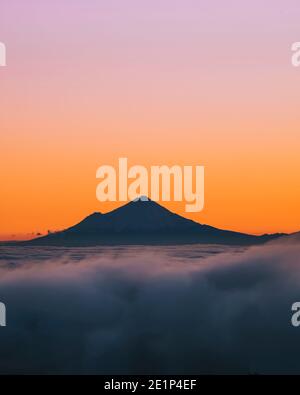Mount Taranaki rising above the mist while sun setting behind, Whakapapa Ski Field, New Zealand Stock Photo