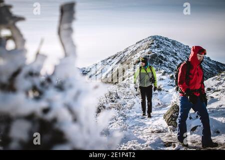 Two winter hikers on snowy frozen trail in mountains of New Hampshire Stock Photo