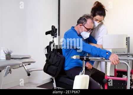 female nurse caregiver, holding patient hand, support disabled patient sit on wheelchair at hospital, young doctor carer help paralyzed patient. High quality photo Stock Photo