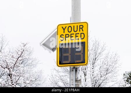 A radar speed sign with snow covered trees in background. Stock Photo