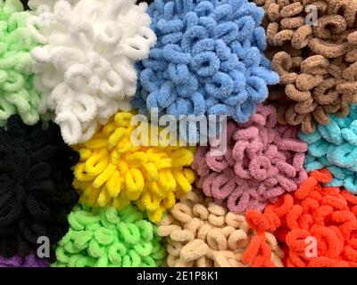 Bright curly multicolored background from a set of plush loopels of yarn blue, yellow, green, brown, beige, white, black, red, orange for hand knitting. Stock Photo