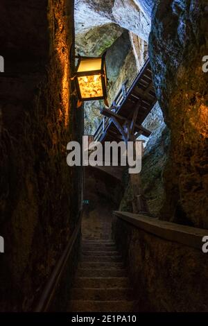 medieval stairway illuminated by lamp in castle with rocks Stock Photo